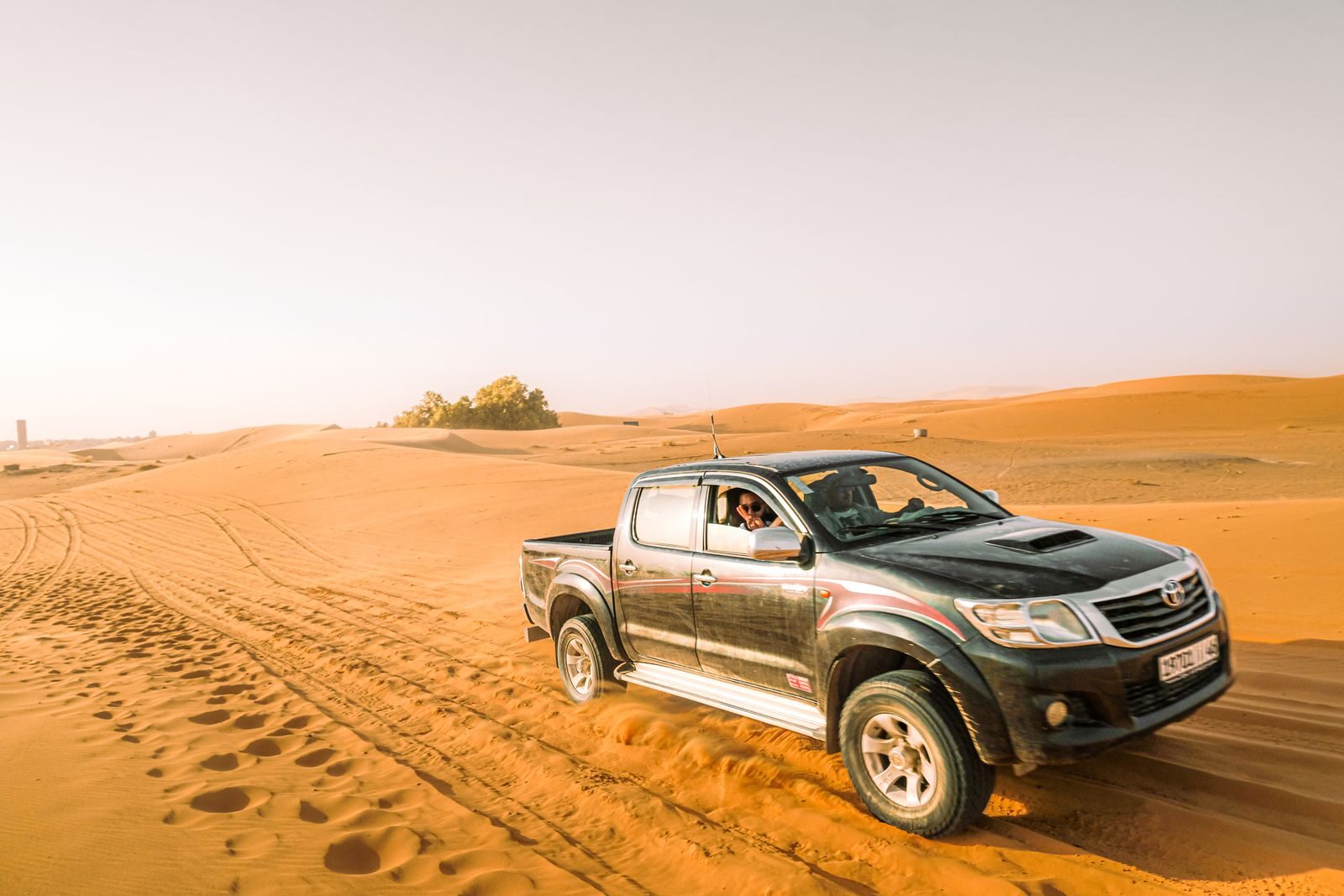 Explore the thrill of off-roading in a rugged pickup truck across expansive desert dunes under bright daylight.