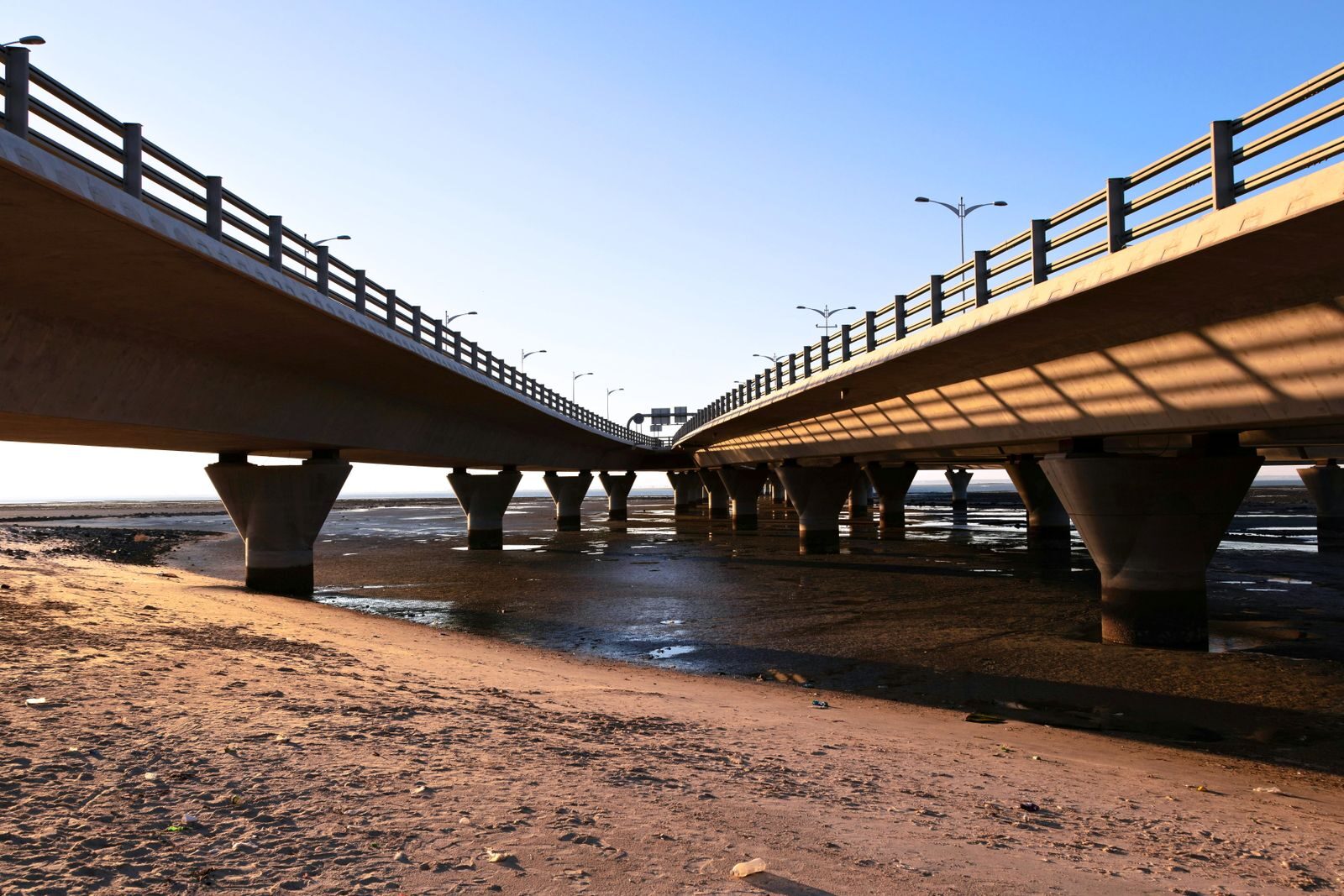 A stunning view of two parallel concrete bridges against a clear blue sky at sunset.