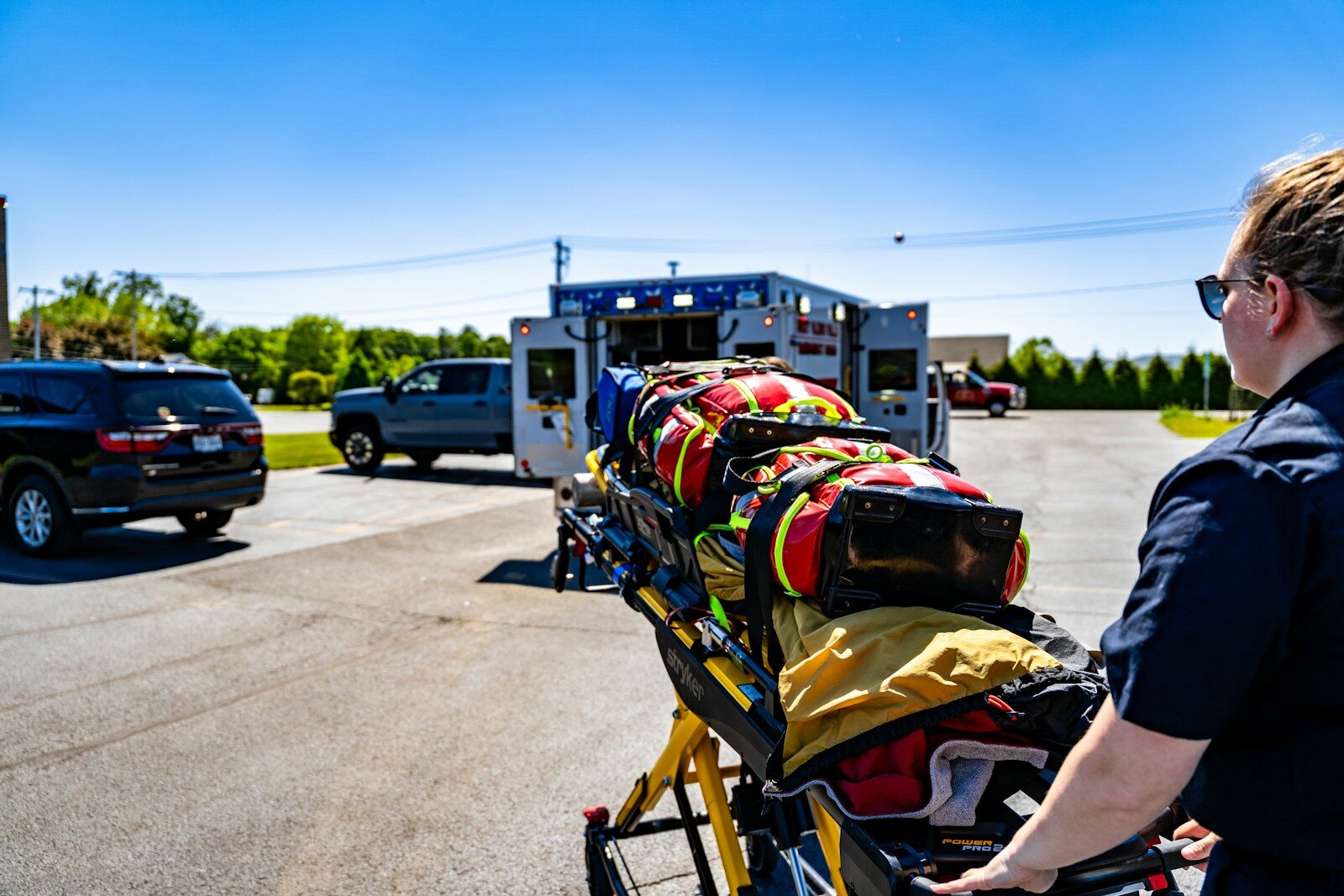 Emt pushing a stretcher towards an ambulance.